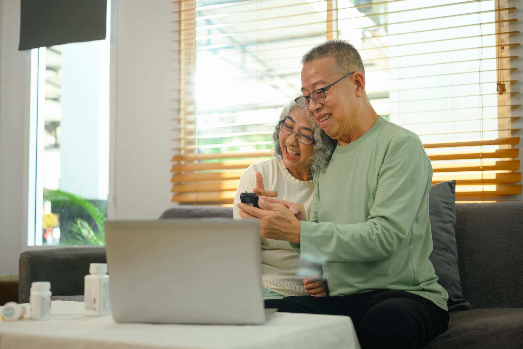 Senior couple having a video call with doctor on laptop in living room. Telehealth concept